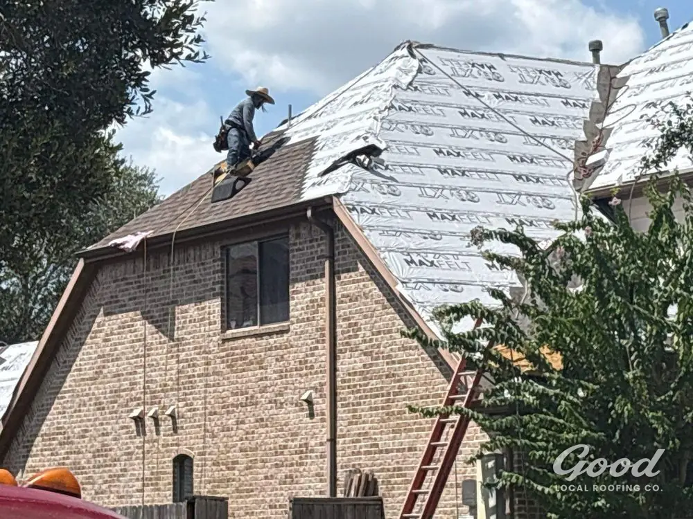 Residential roof dried in with underlayment while crew works near the ridge.