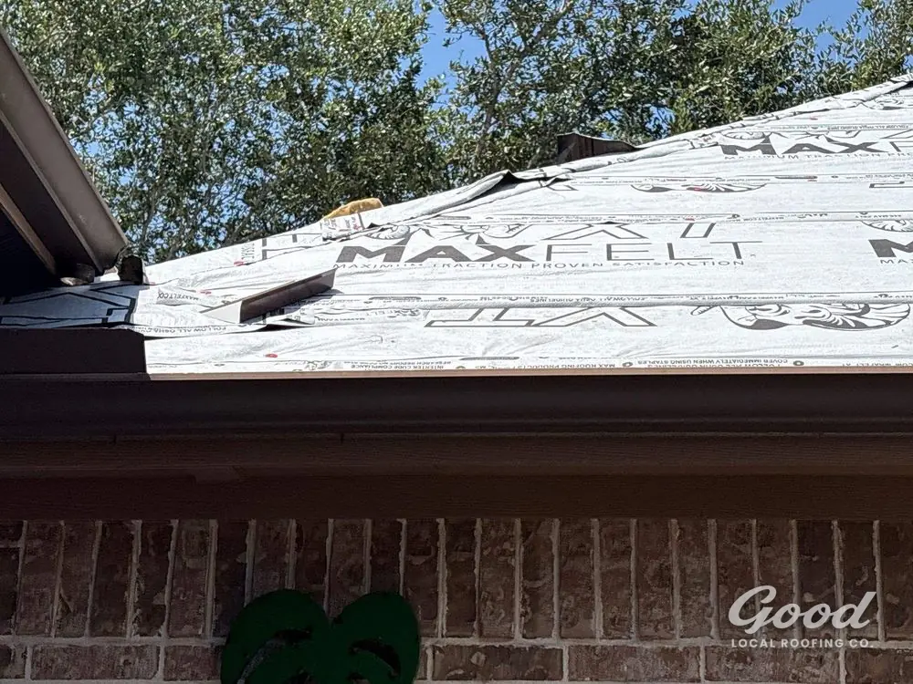 Roof edge showing drip edge and gutter line beneath installed underlayment.