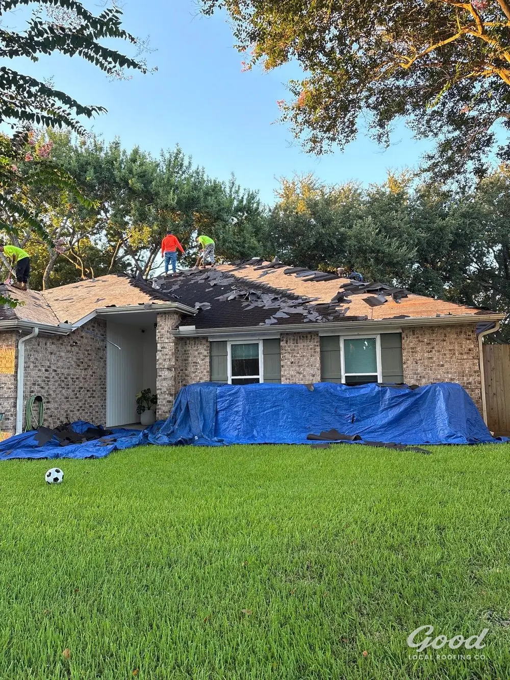 Ground covers and tarps protecting landscaping beside a home during roof replacement.