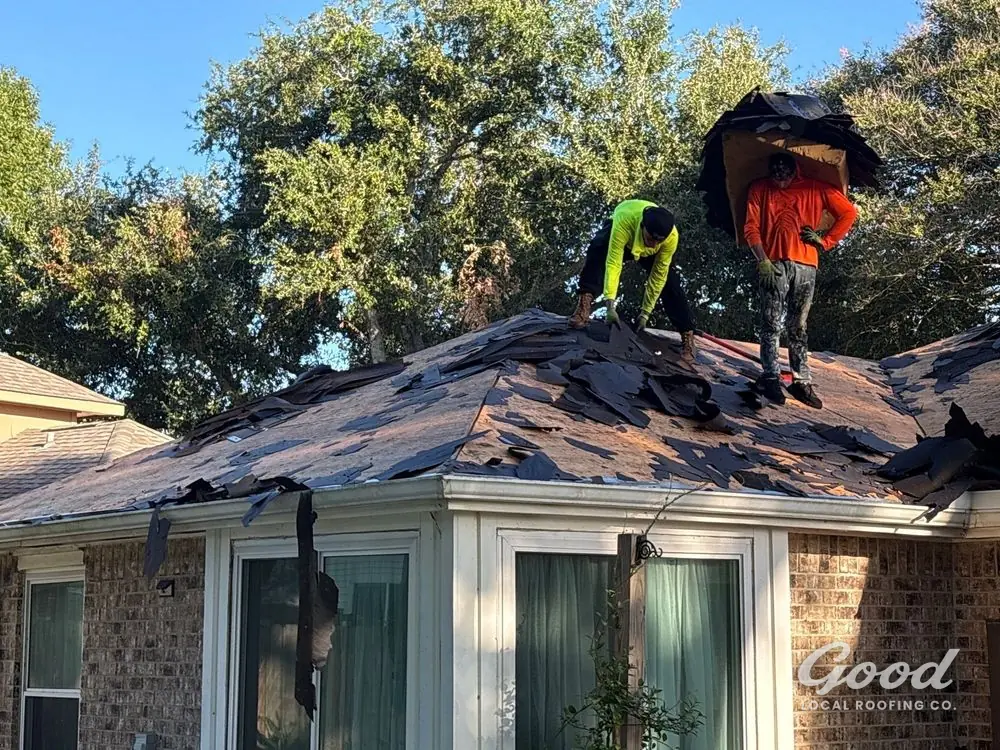 Crew removing existing roofing material from a residential roof during tear-off.